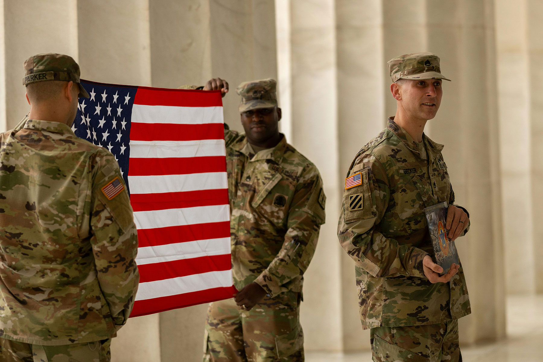 Soldiers in uniform holding an American Flag